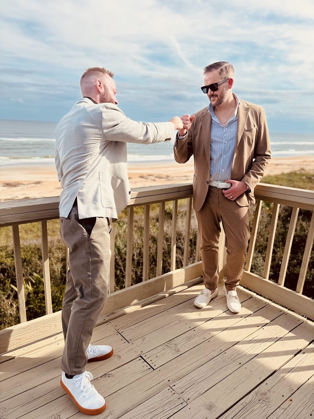 Two Button Up operators in suits on a beachfront balcony